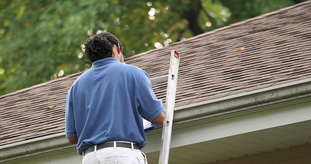 Insurance claim inspector on ladder